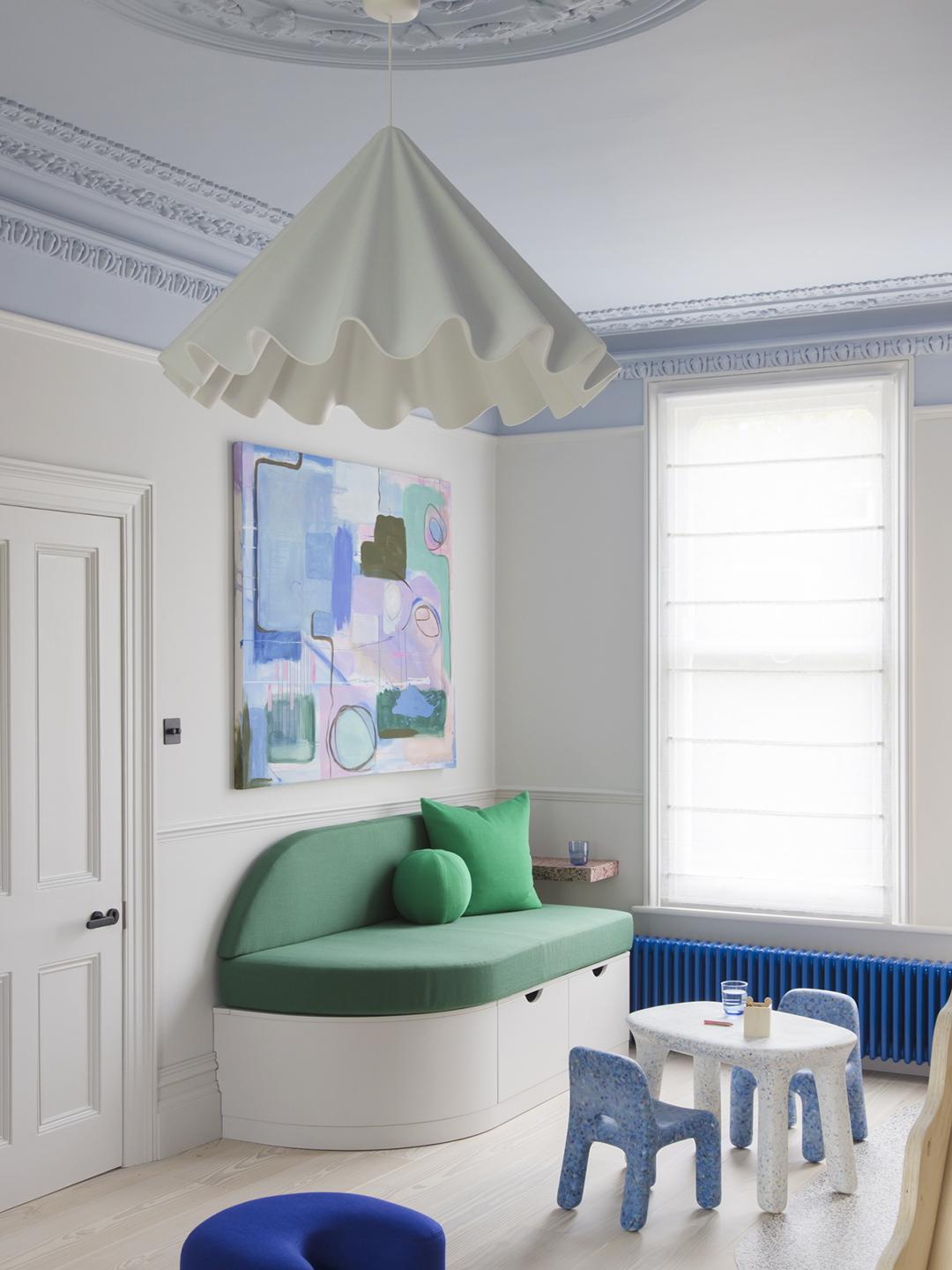 Kids' room with frilly white pendant lamp and green banquette sofa.