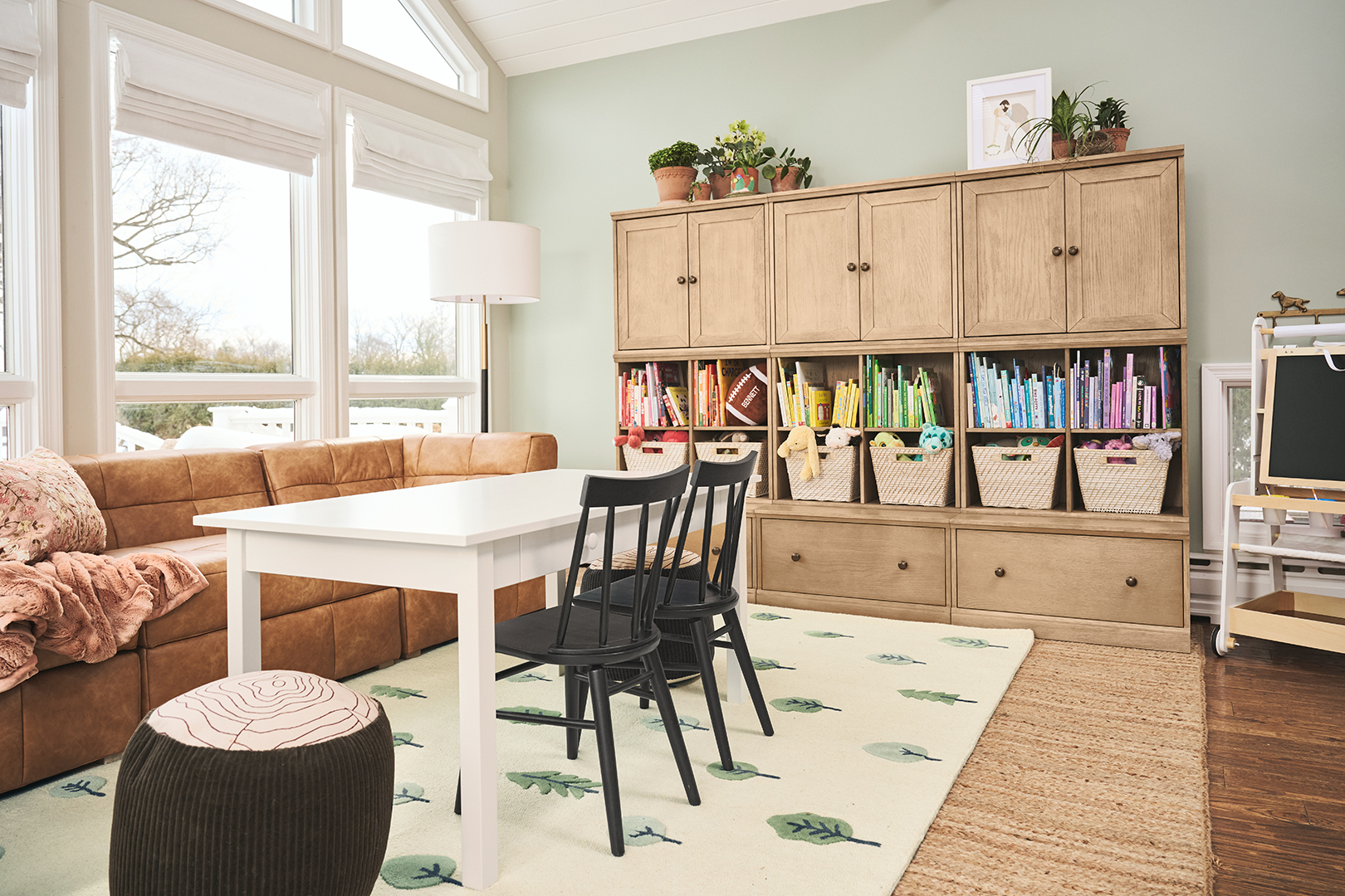 Horizontal shot of playroom storage shelves and white table with black chairs