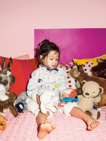 Little girl on her bed surrounded by stuffed animals