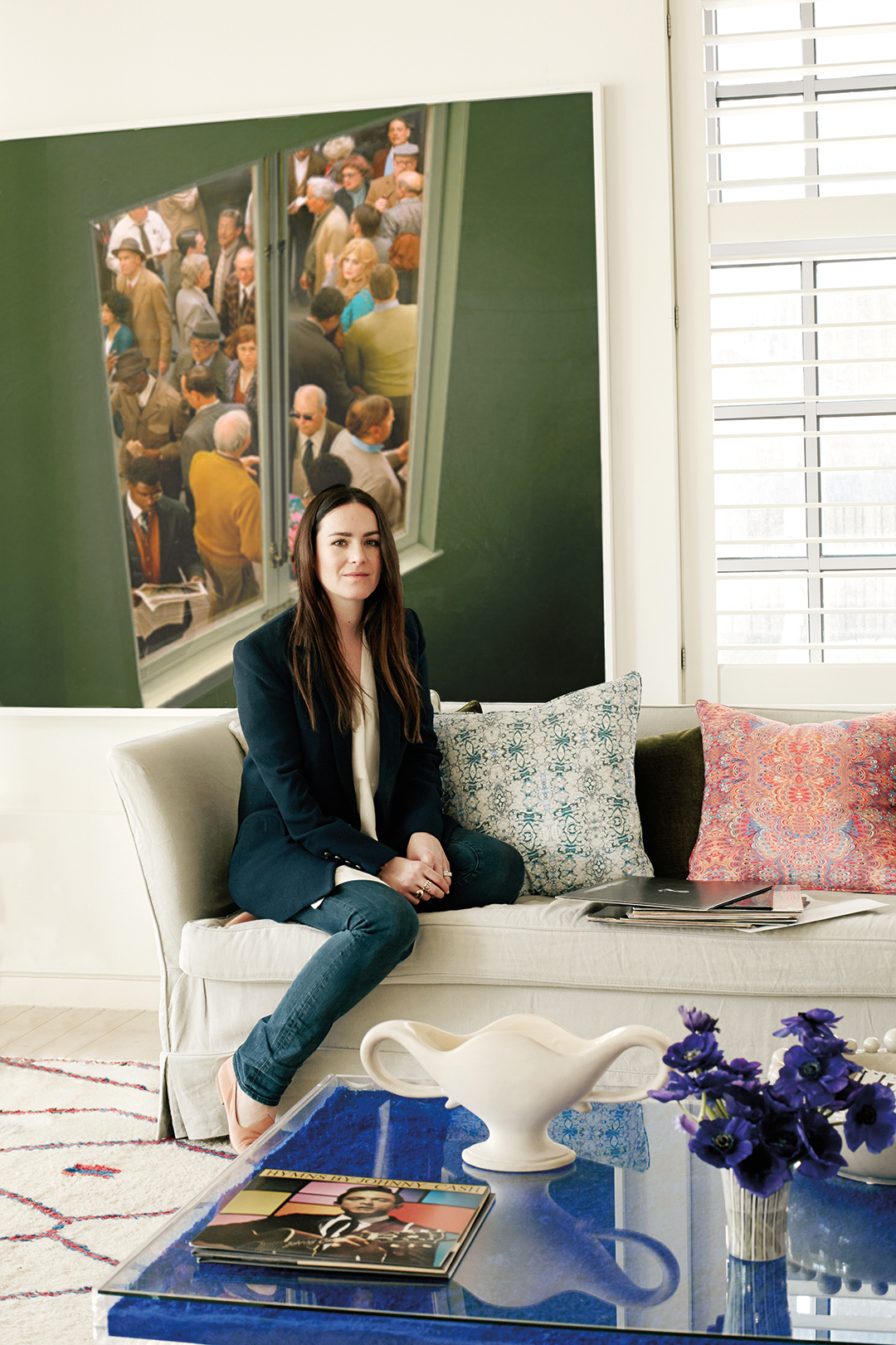 Woman sitting on white sofa against a green wall with art on it