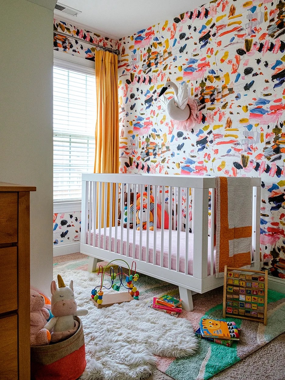 Nursery with paintbrush stroke wallpaper and white crib.