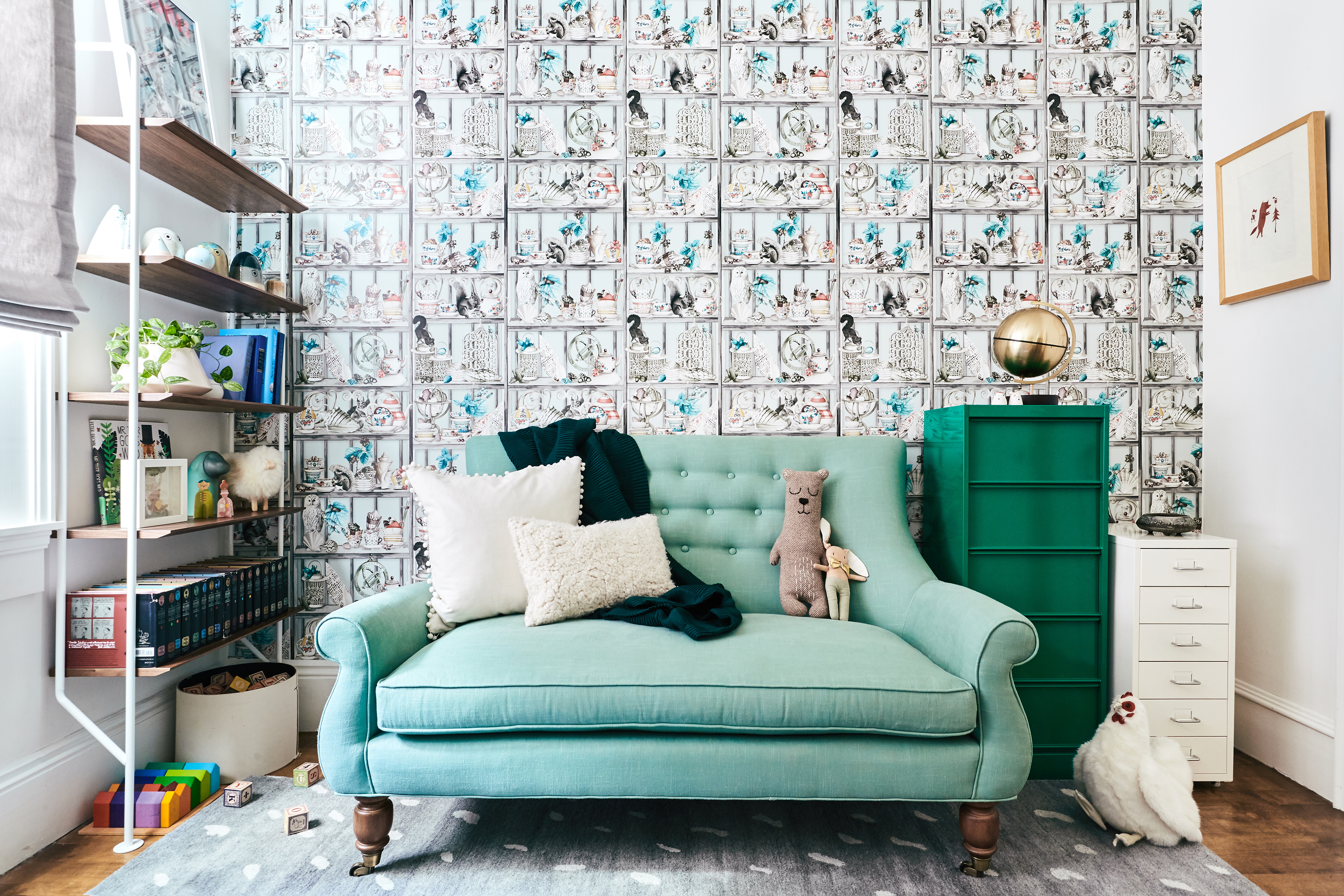 living room with sea green couch and wallpapered wall