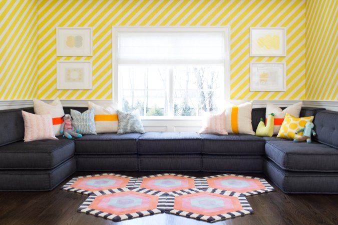 sectional couch in front of yellow and white striped wallpapered wall