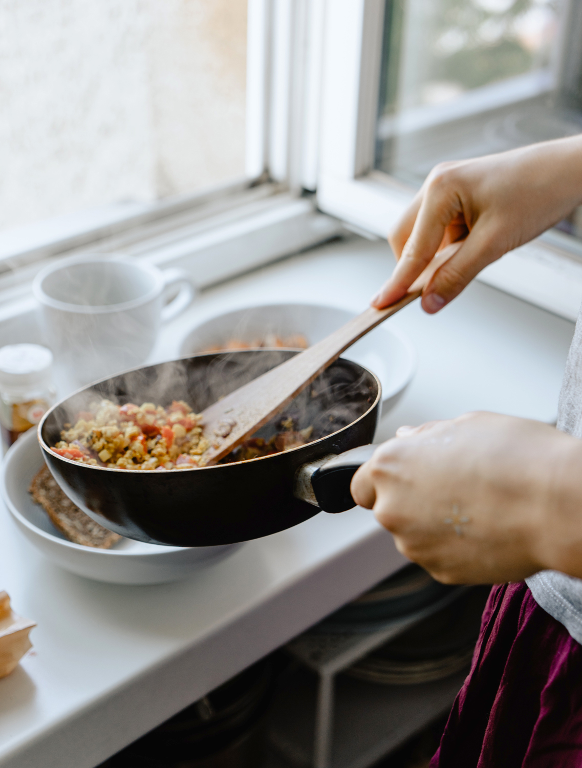 person plating breakfast from a skillet