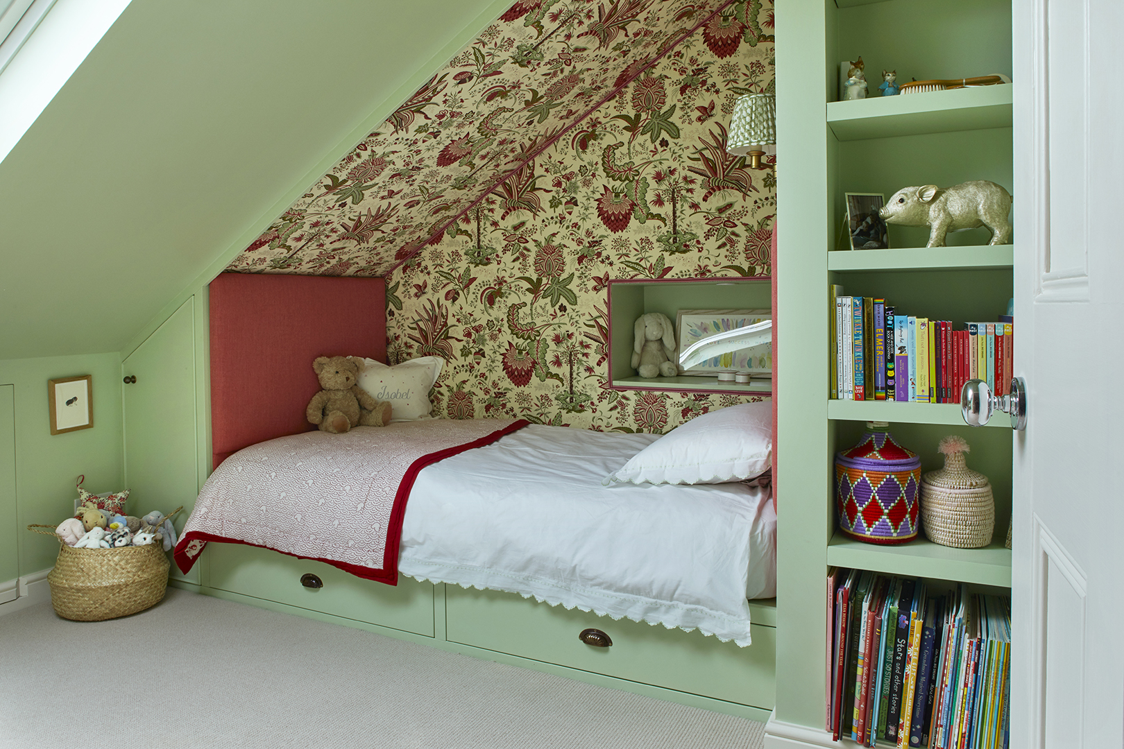 Girl's bedroom with pistachio-colored walls and bed nook with red floral fabric.