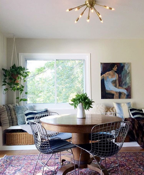 domino magazine dining room with tiny circular table and wire chairs