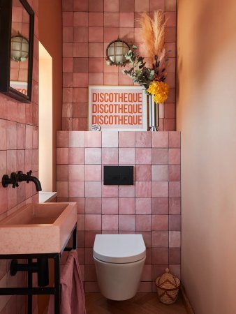 Pink-tiled small bathroom with pink sink and artwork that says "Discotheque."