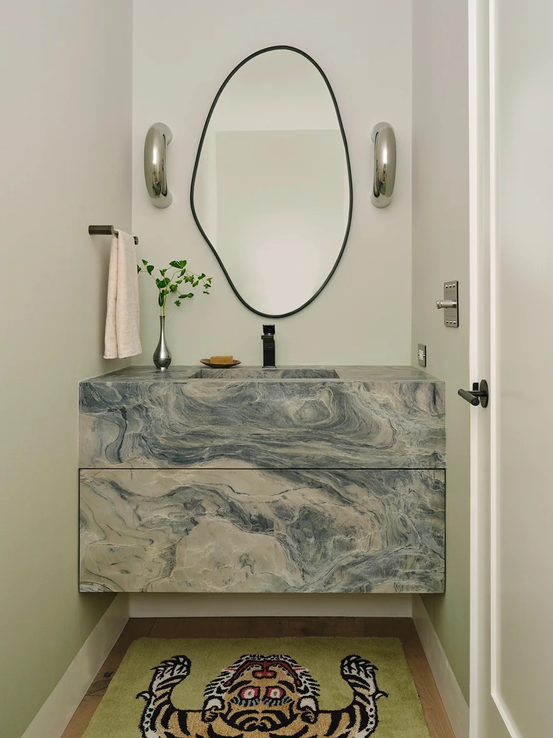 Small bathroom with blue stone floating vanity and tiger rug.