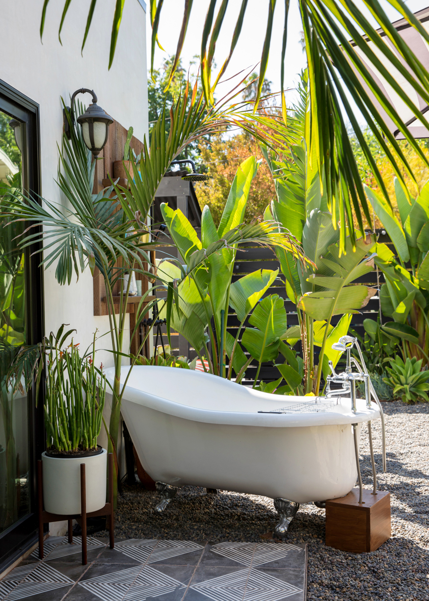 patio with black concrete painted tile bathtub and large plants