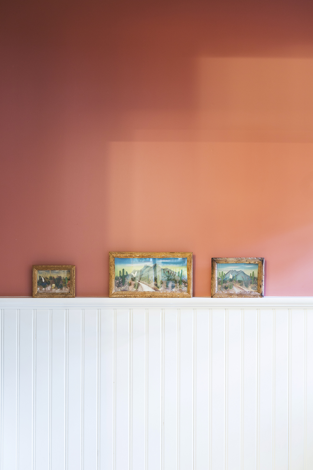 Orange wall with wainscoting and art