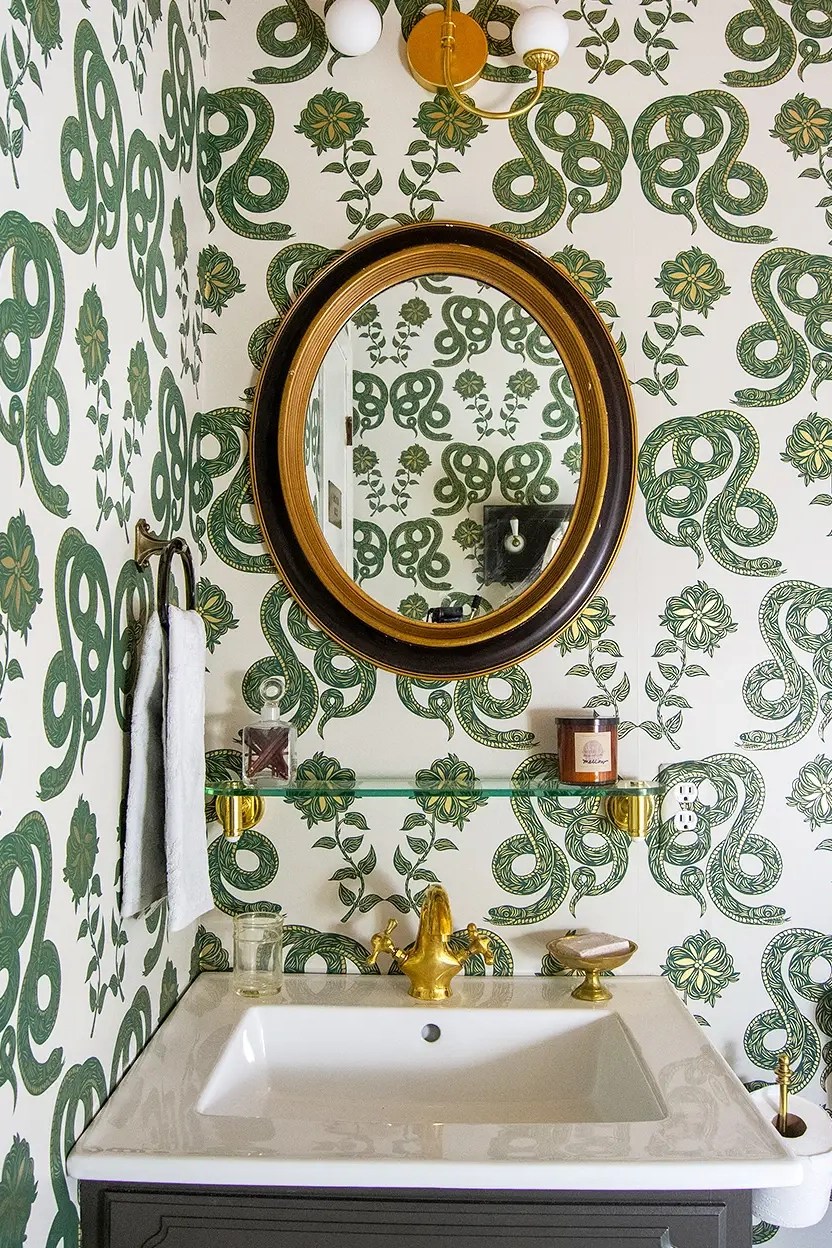 Bathroom with black oval mirror, and snake print wallpaper.