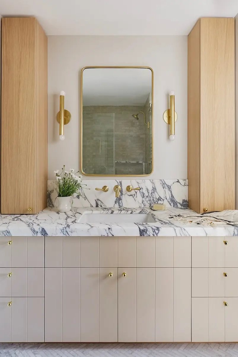 Bathroom with beige vanity, marble countertop, and wood storage cabinets on the sides.