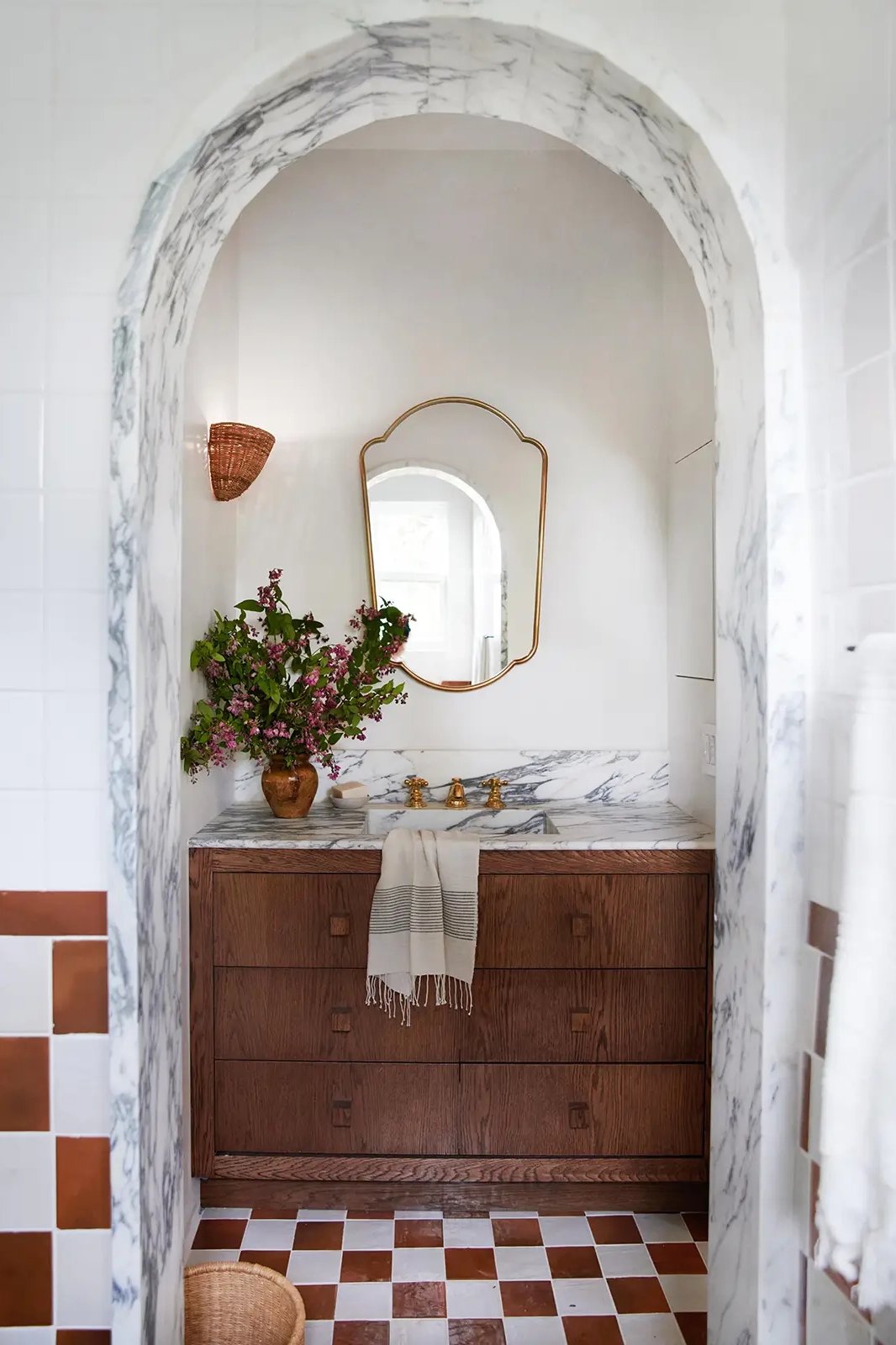 Bathroom with marble-lined arch and wood vanity.