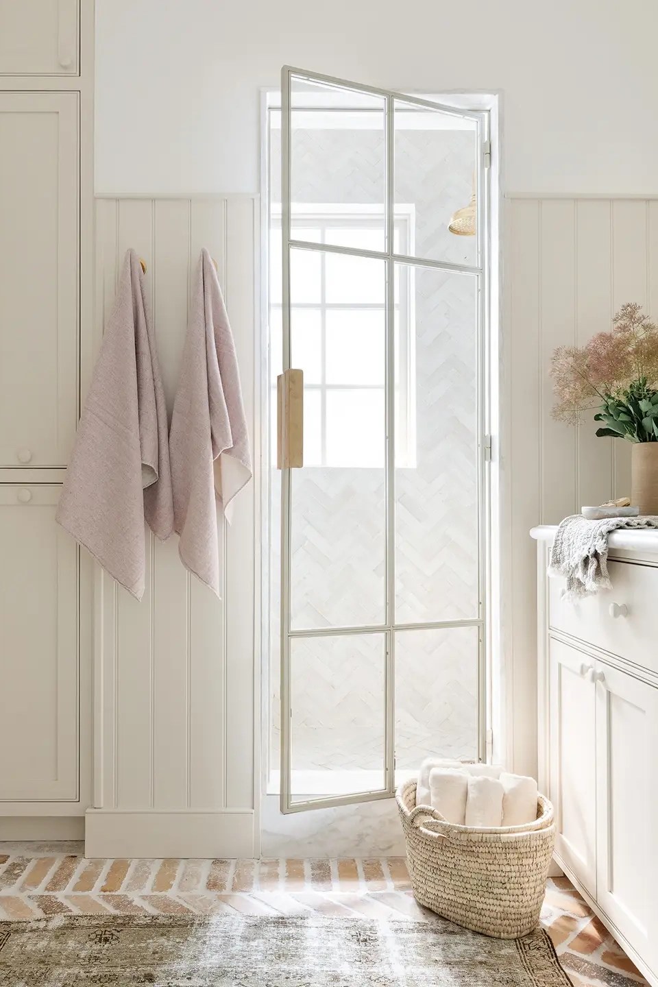 All-white bathroom with metal and glass shower door.