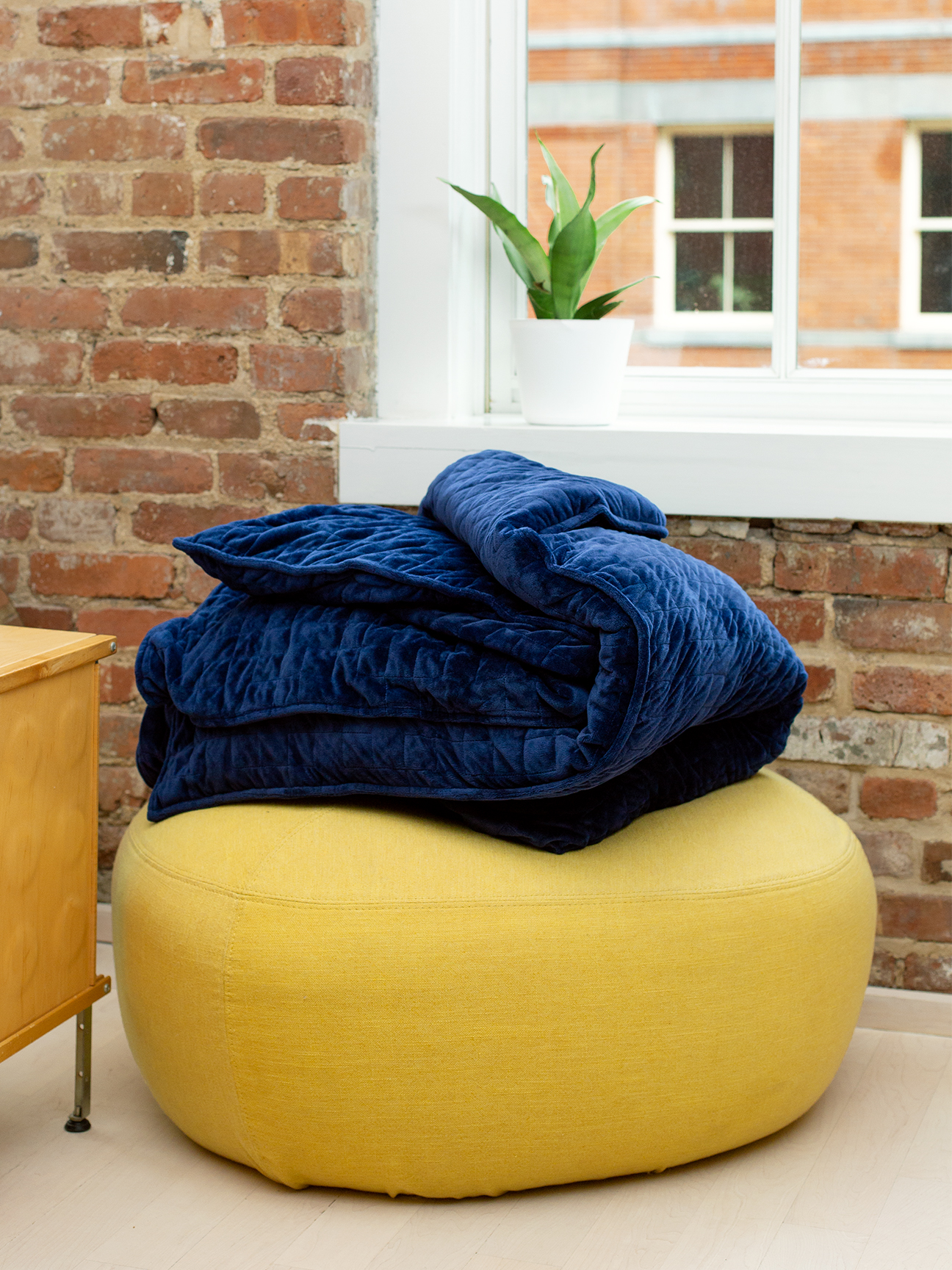 Yellow pouf with blue blanket.