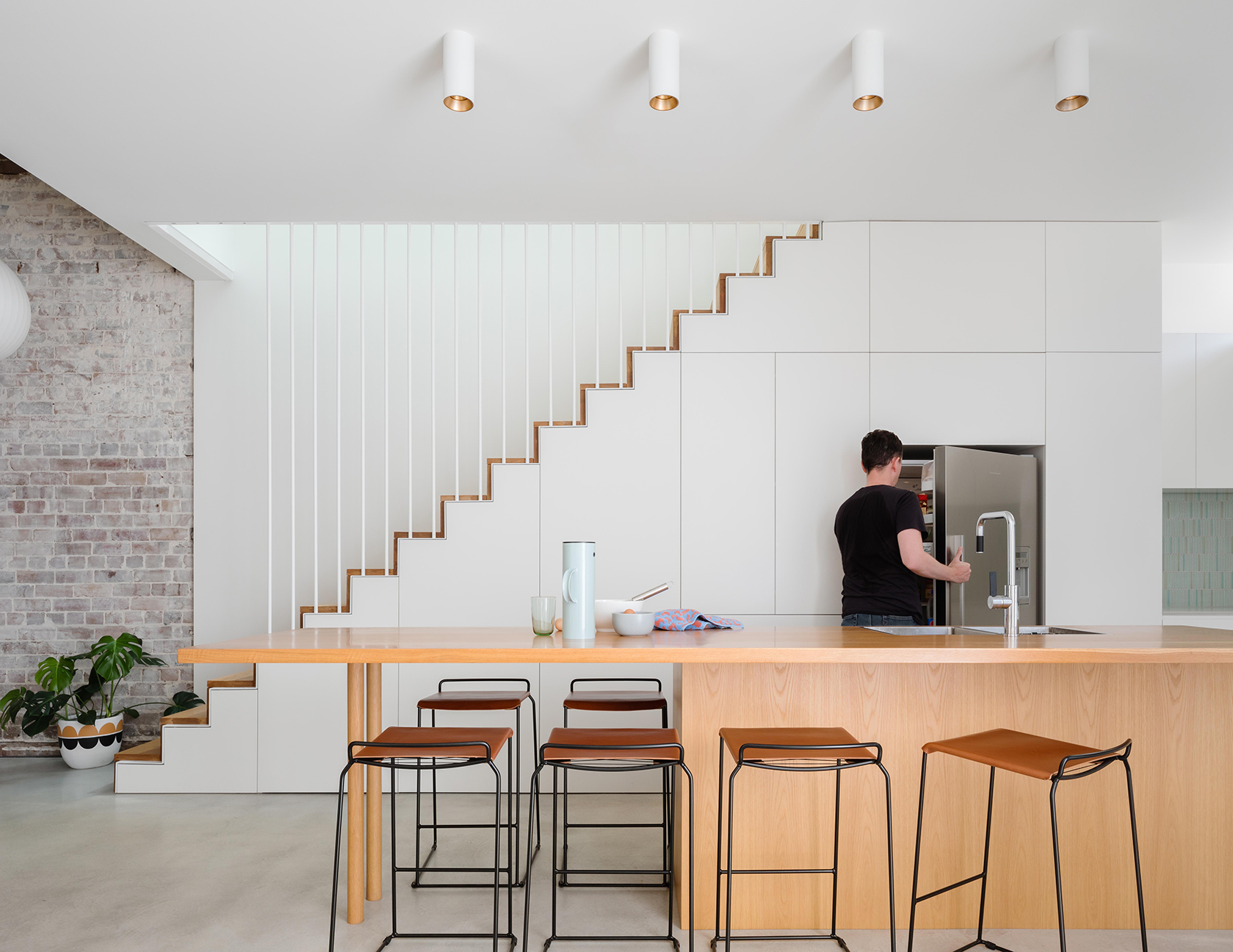 white kitchen cabinetry beneath steel staircase