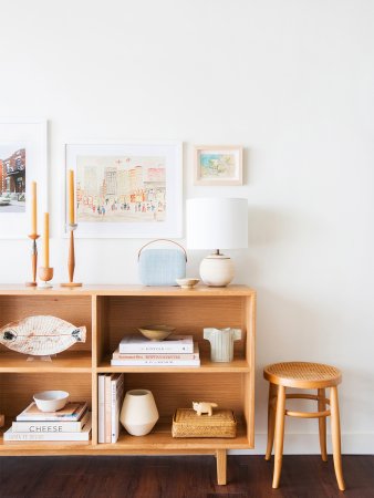 wood console with open shelves, topped with stacks of books