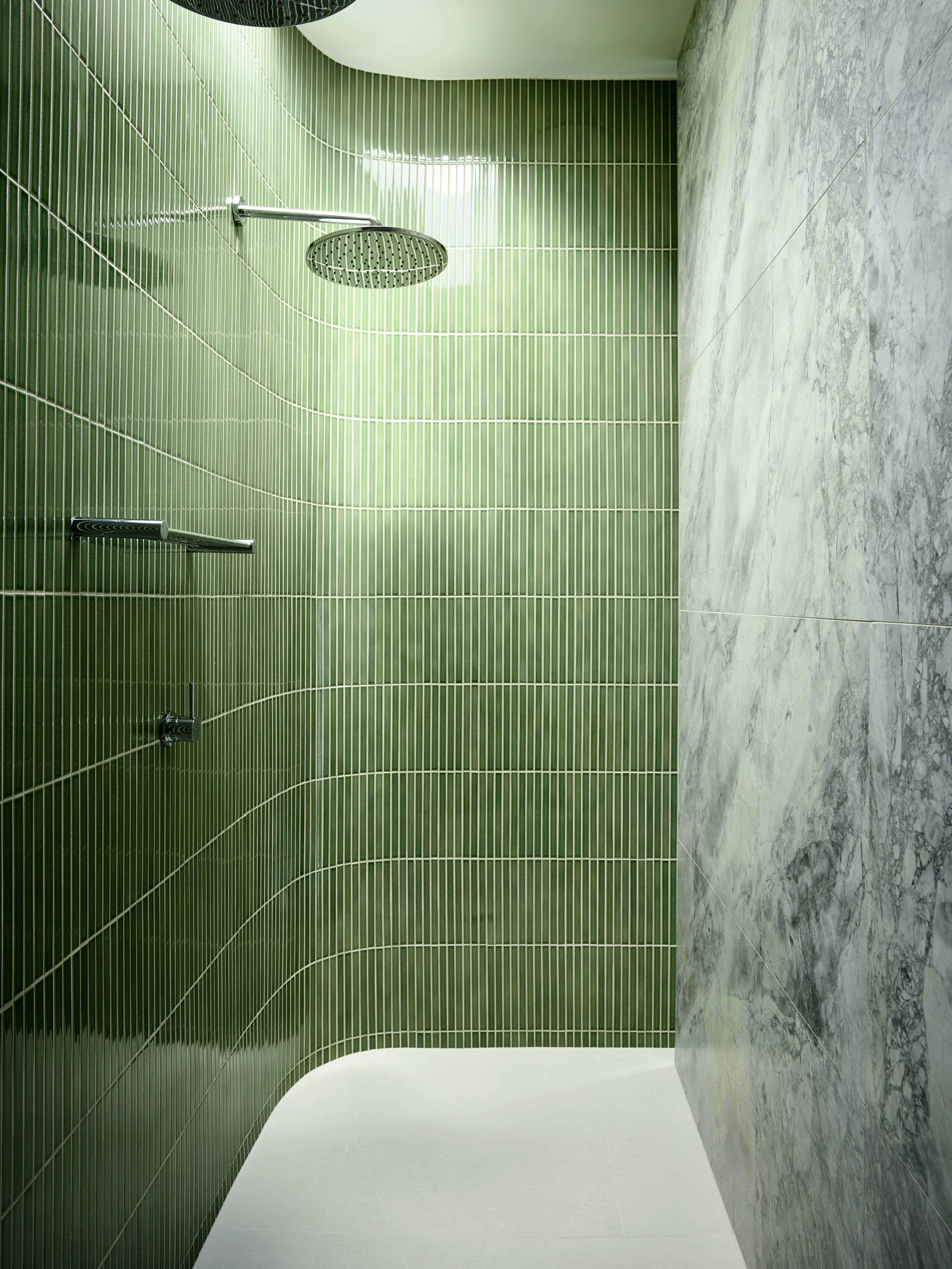 curved shower with long narrow green tiles