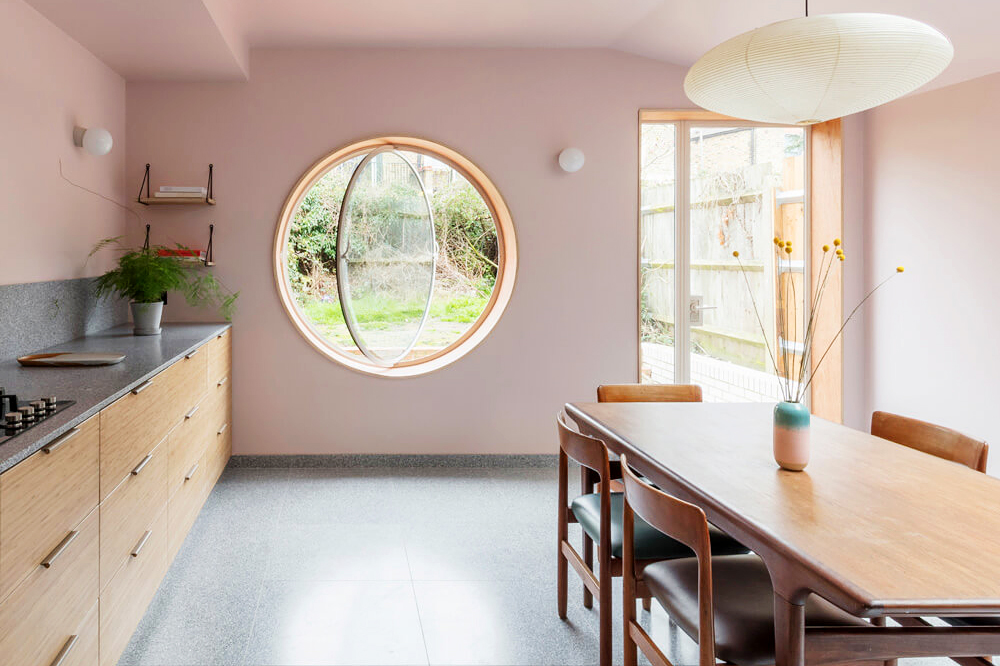 pink kitchen and dining room with an open round window