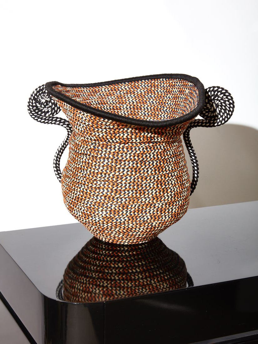 a braided cord urn sitting on a black table