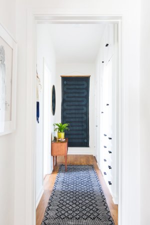 white hallway with a blue runner and blue wall hanging at the end