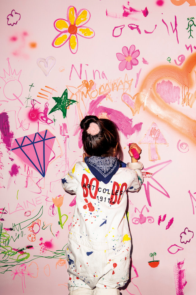 little girl scribbling on a pink wall