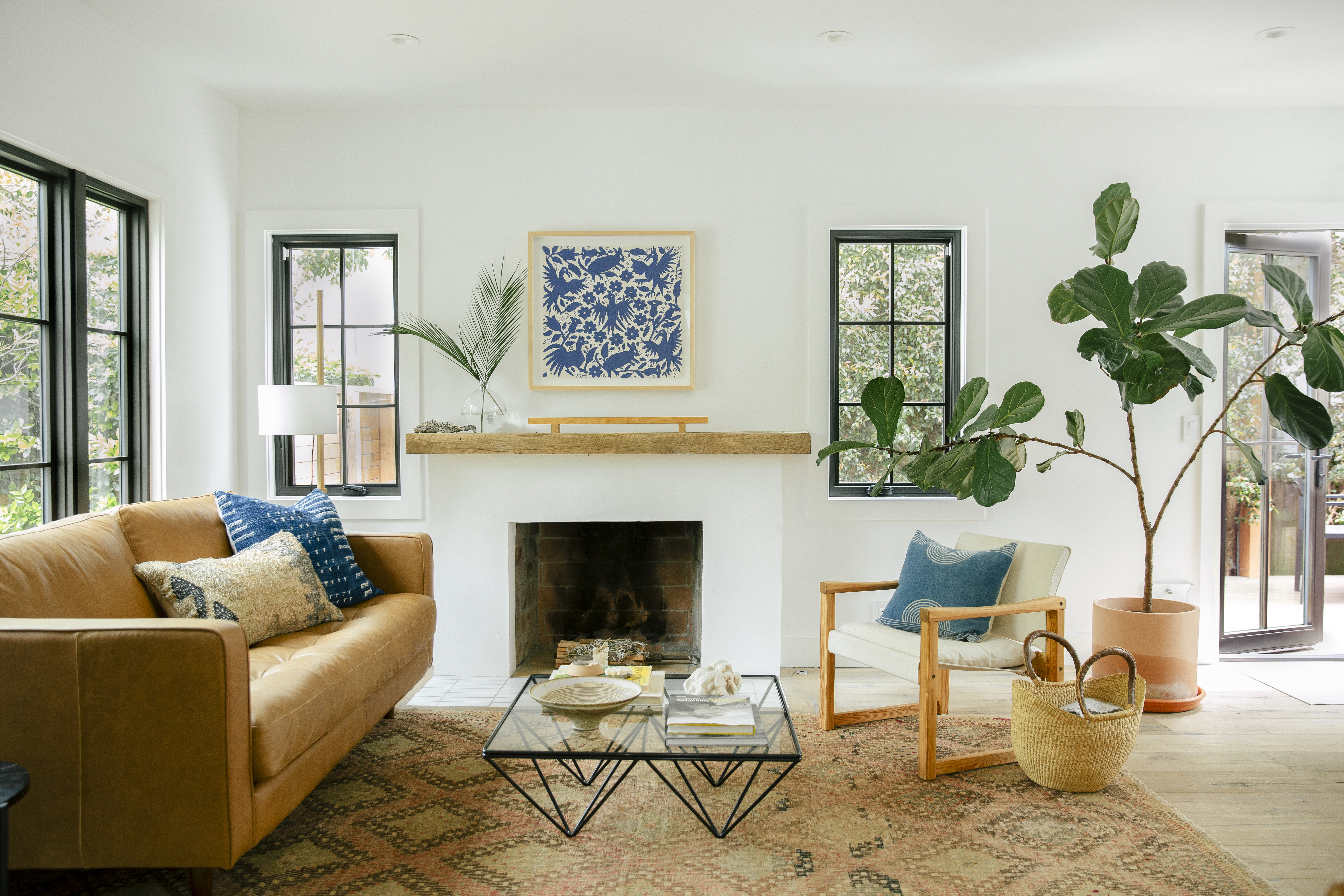 living room with brown leather sofa, vintage rug, black metal table, and white lounge chair