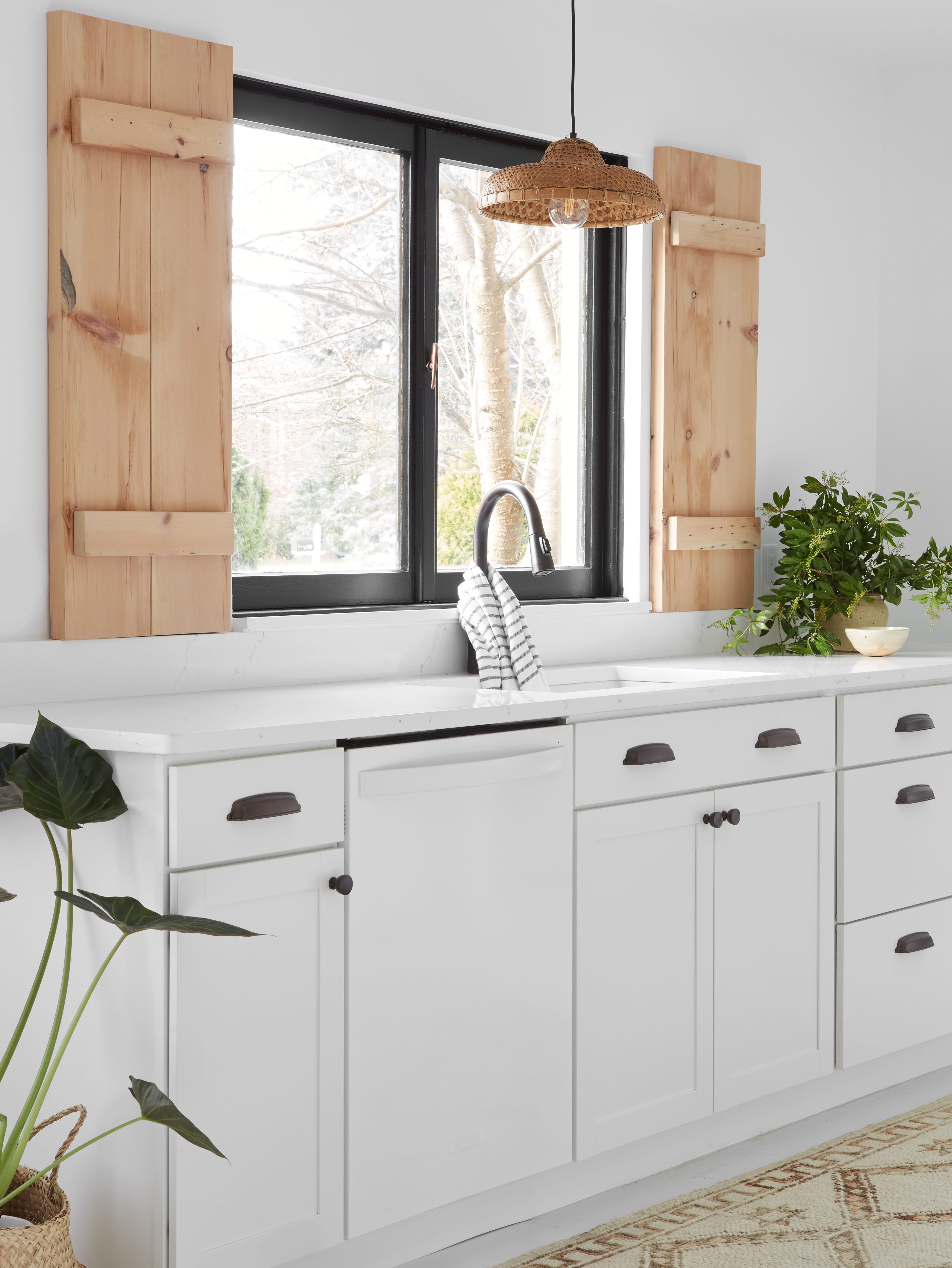 white kitchen sink area with raw wood shutters by the window
