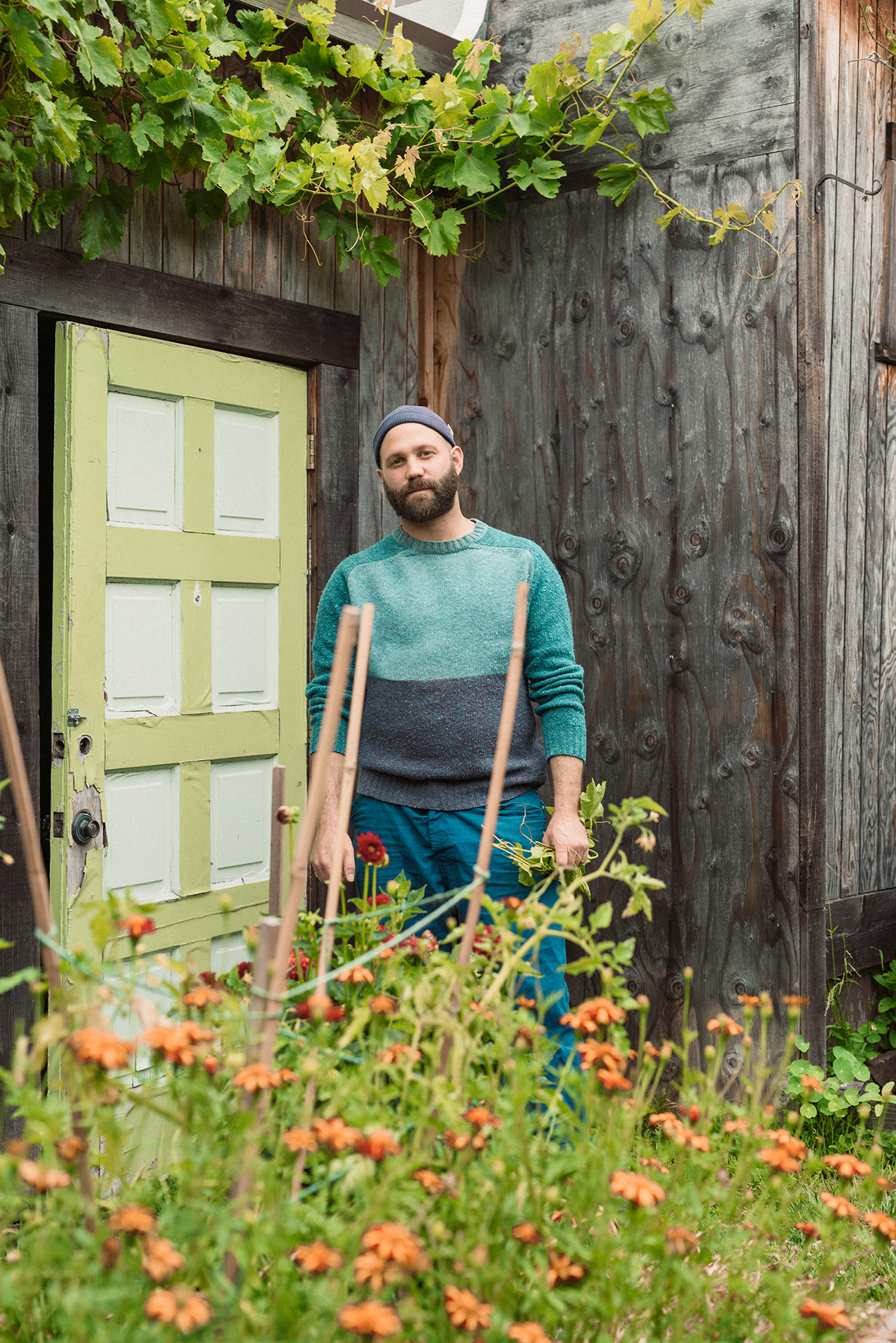 man standing in front of weathered home exterior with plants