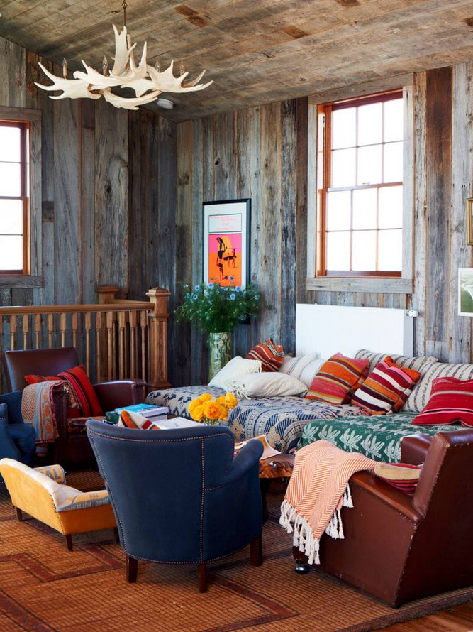 cozy cabin living room with a deer antler chandelier and daybeds coverd in blankets