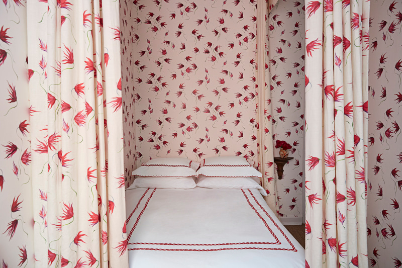 red floral drapery around a bed that matches the walls