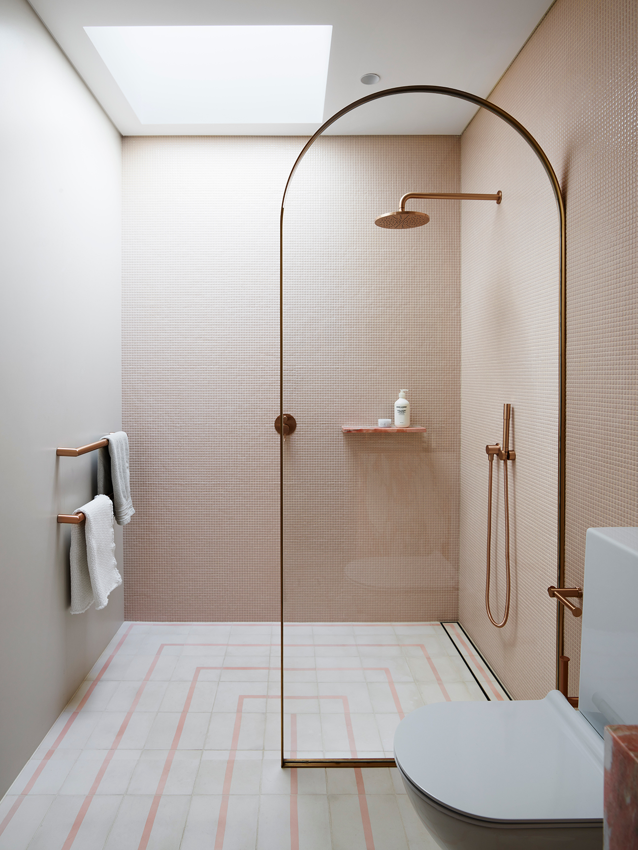 glass shower arch partiion in a pink bathroom