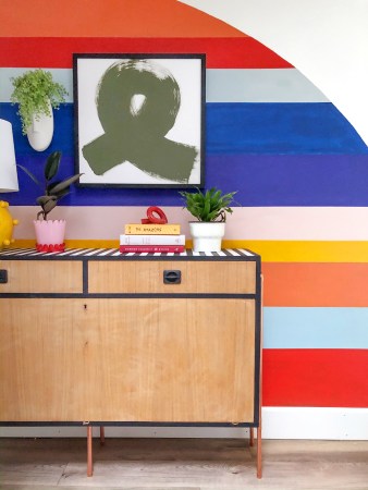 striped rainbow wall with a sleek credenza