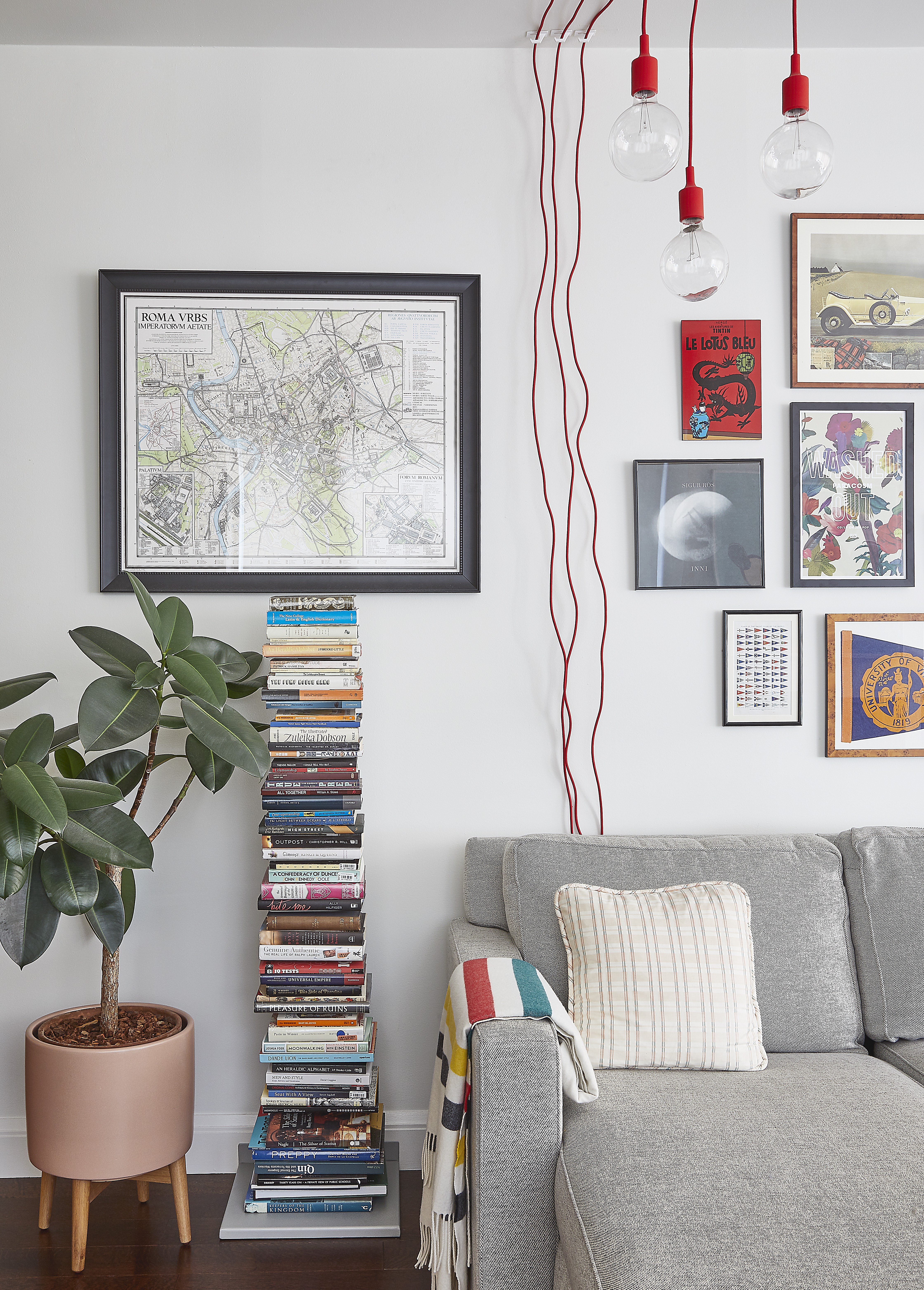 Room with a sofa, stack of books, and hanging exposed lightbulbs