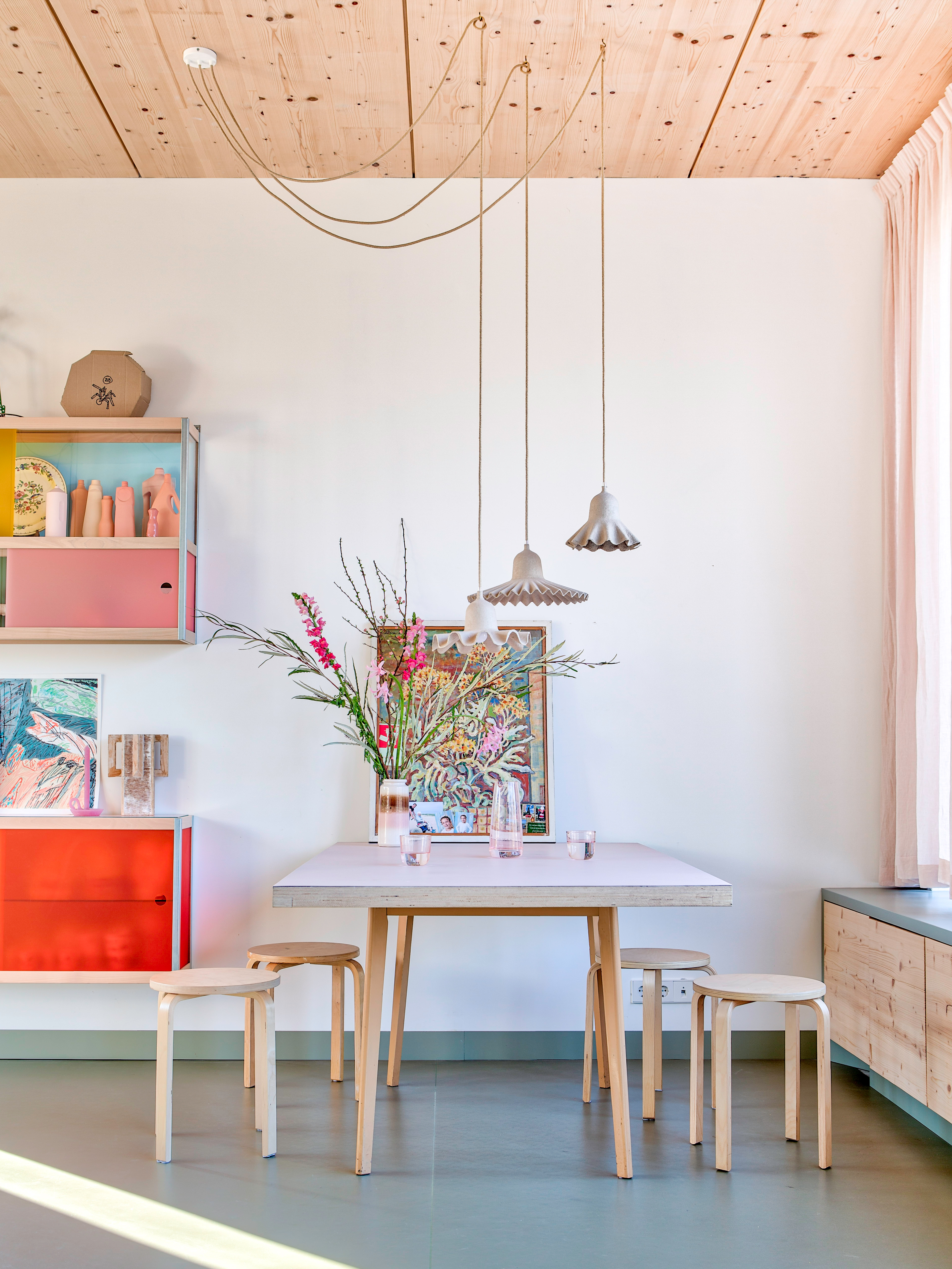 Kitchen with white walls, light wood table and chairs, and colorful wall cabinets