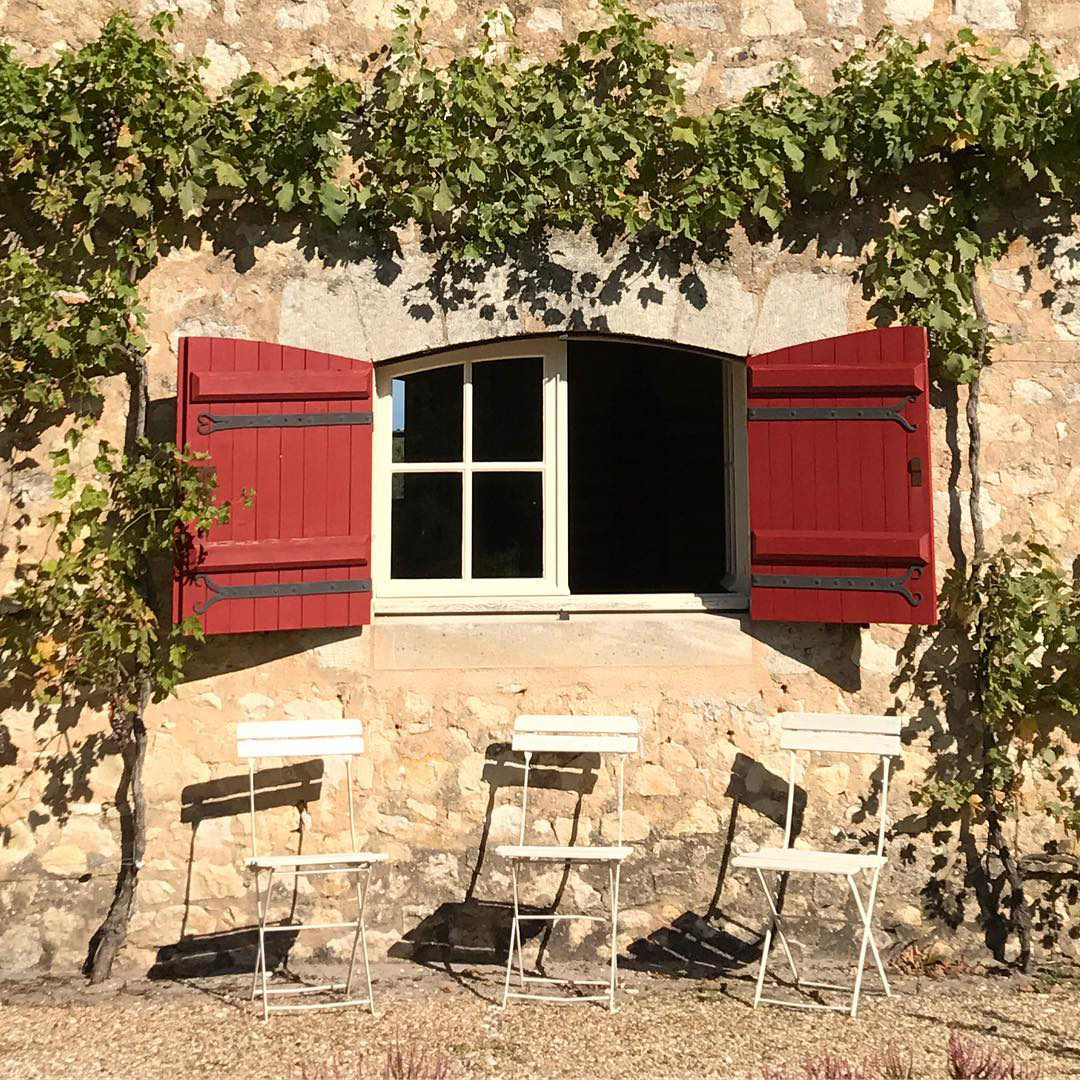 old house with red shutters and white chairs outside