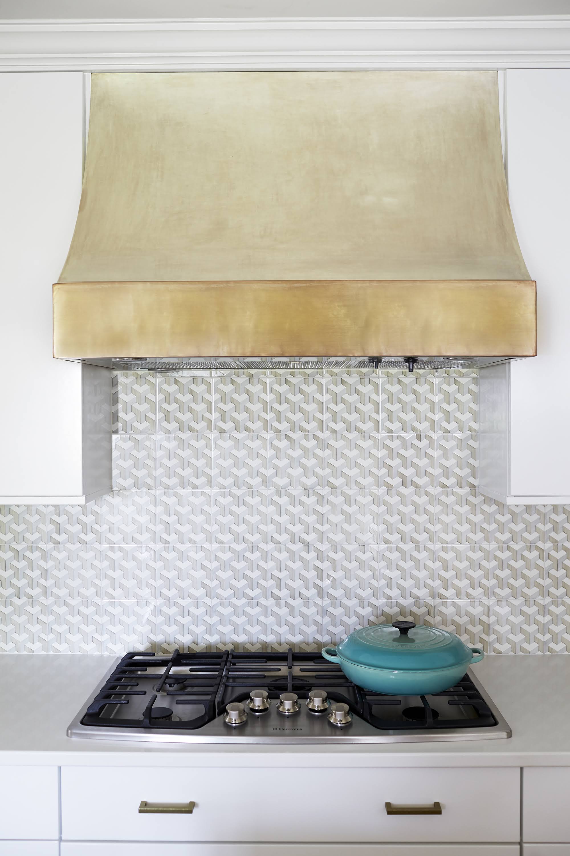 white kitchen with gold oven vent and blue dutch oven