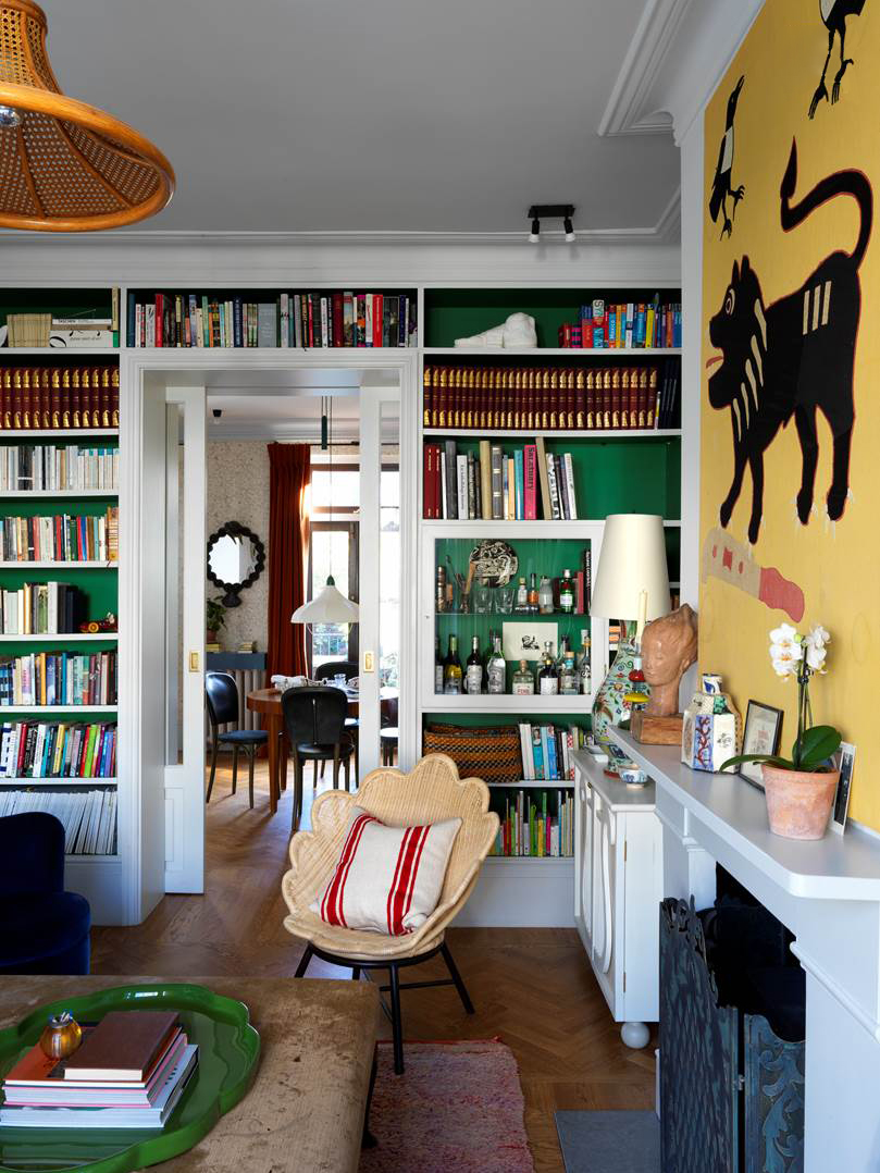 Living room with green bookcases and yellow art