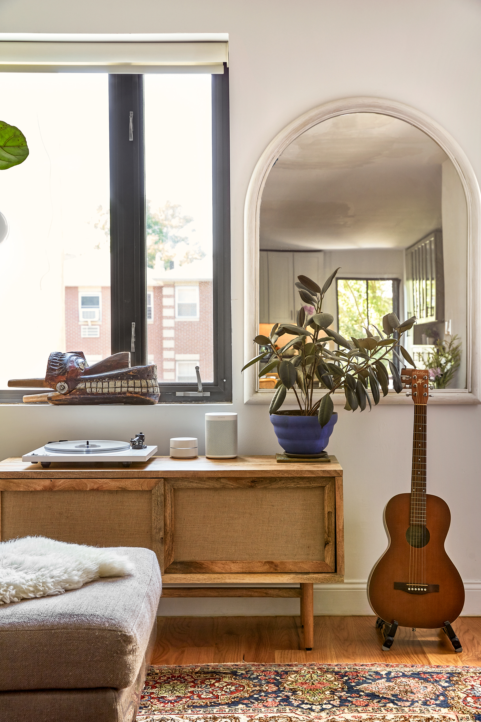 rattan console underneath mirror and guitar