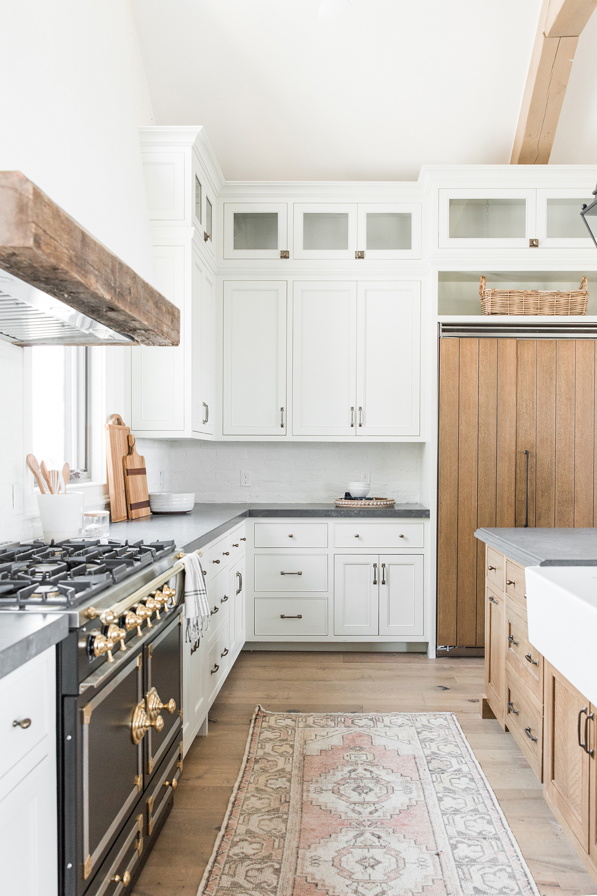 white kitchen with black range and wood detailing above the hood