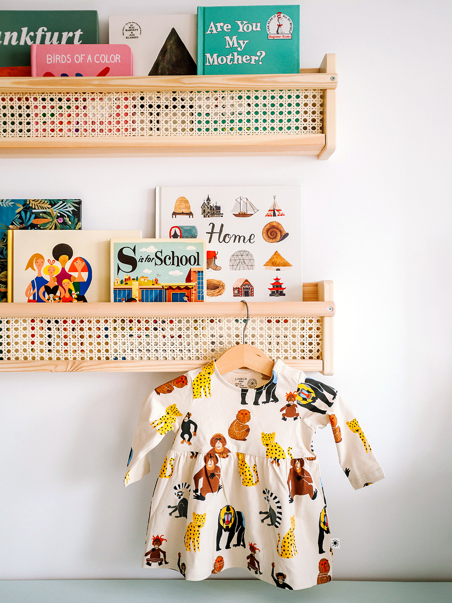 baby clohtes hanging from edge of a shelf