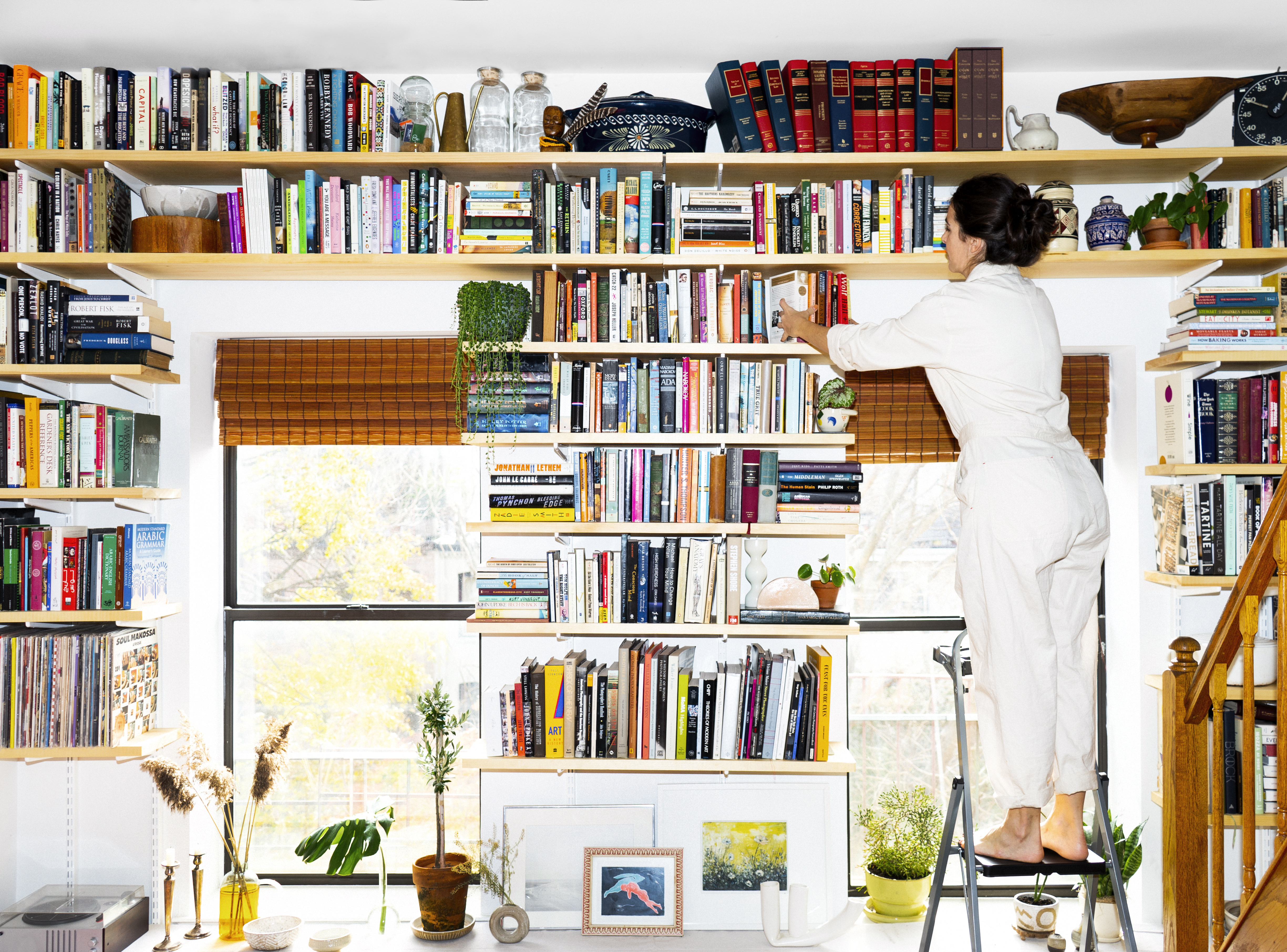 woman on a ladder arranging books