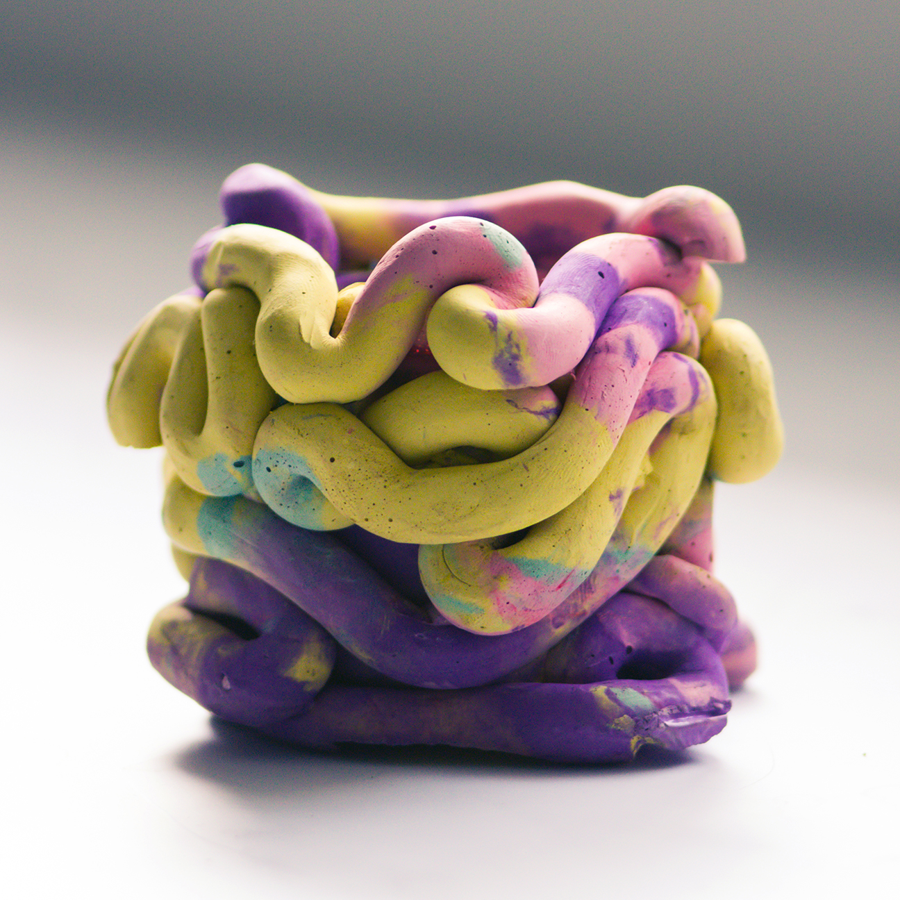 yellow pink and purple vase made up of squiggly parts