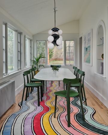 rainbow rug and dining table on it with green chairs