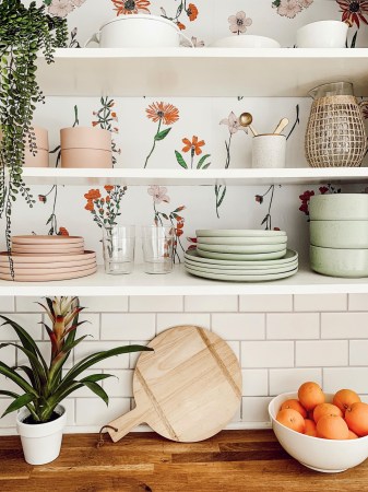 open shelves with wallpaper floral design and mint and pink plates