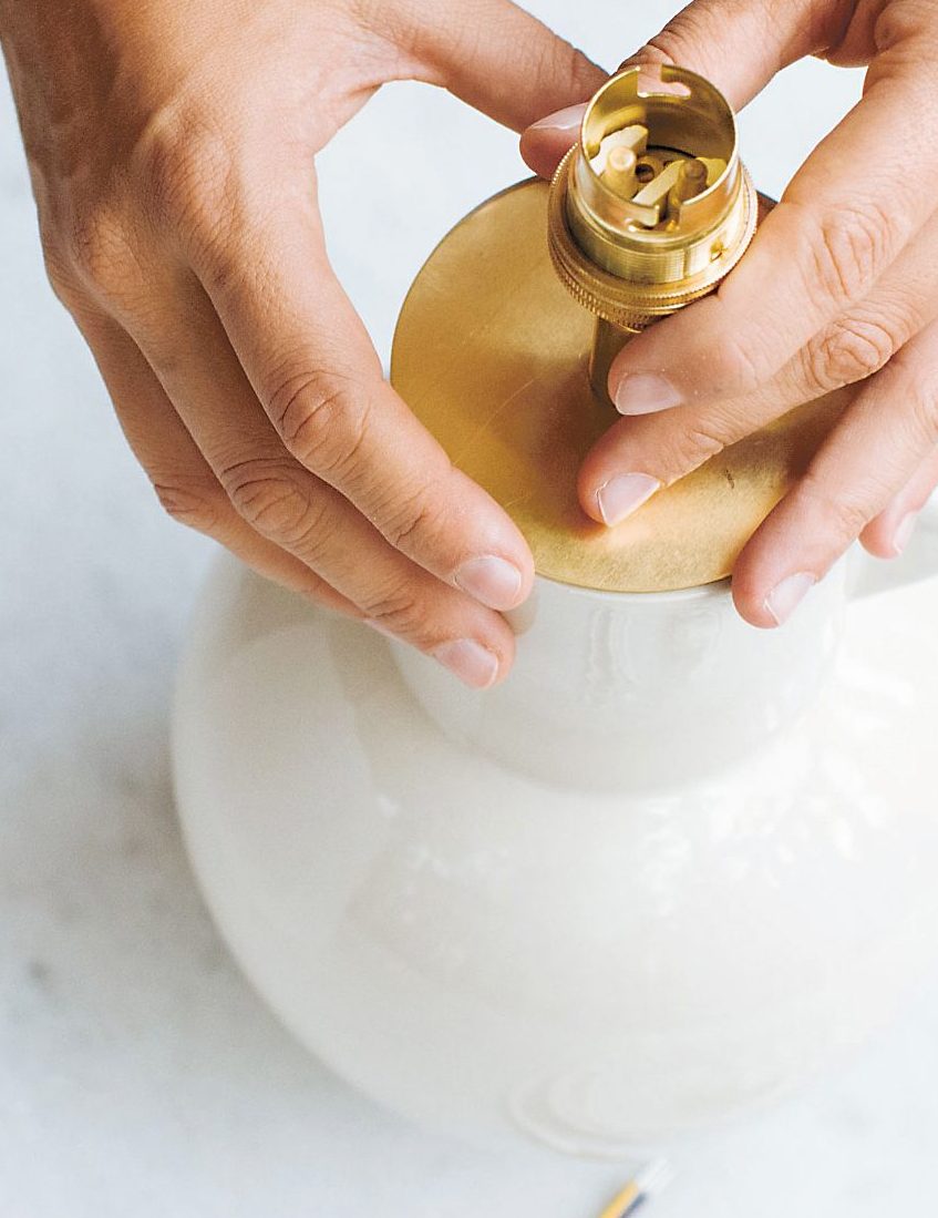 woman screwing on a gold top to lamp