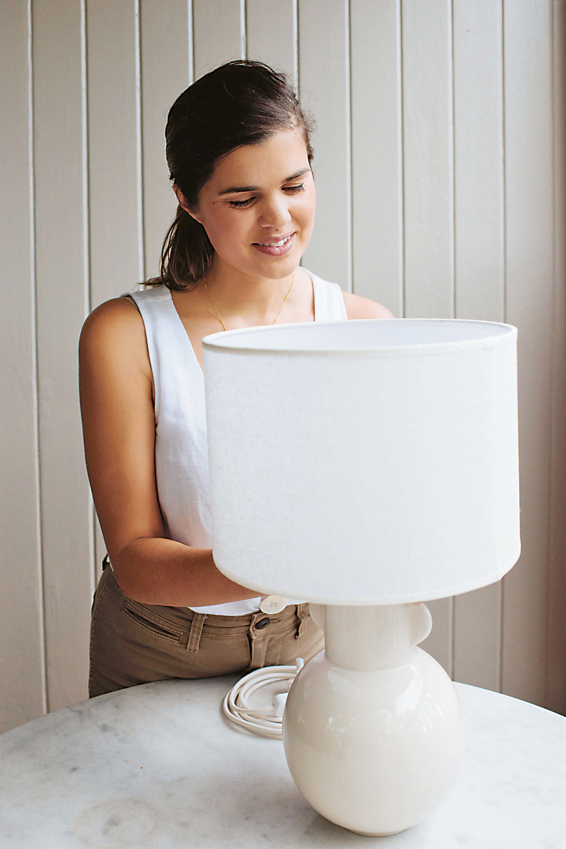 woman putting on a lamp shade