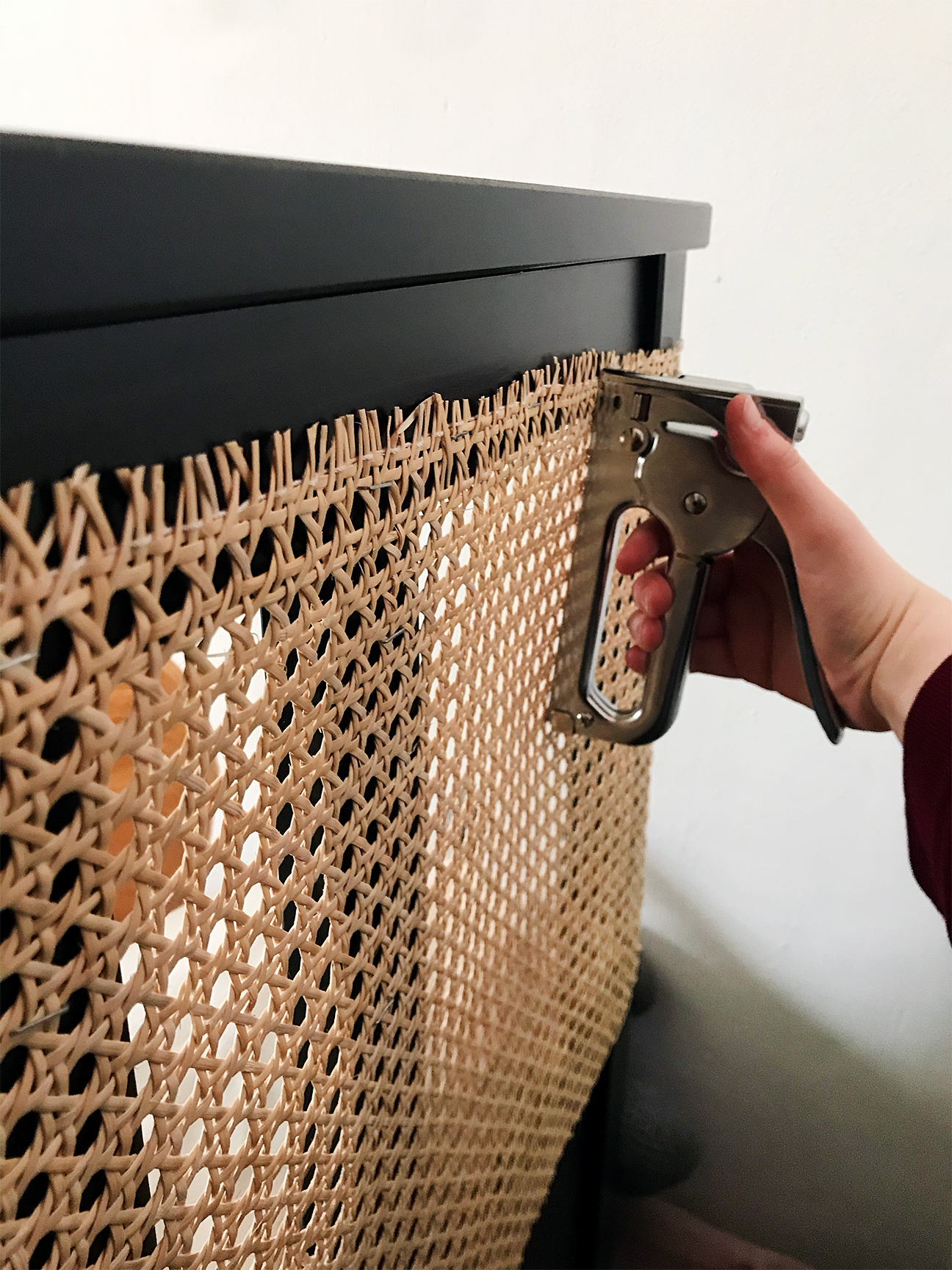 Caning being stapled to headboard