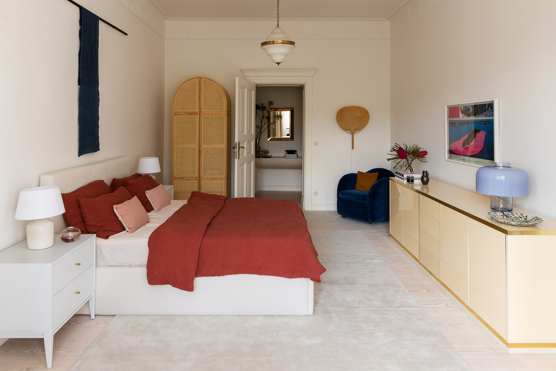 bedroom with red bedding lacquer credenza and cane wardrobe