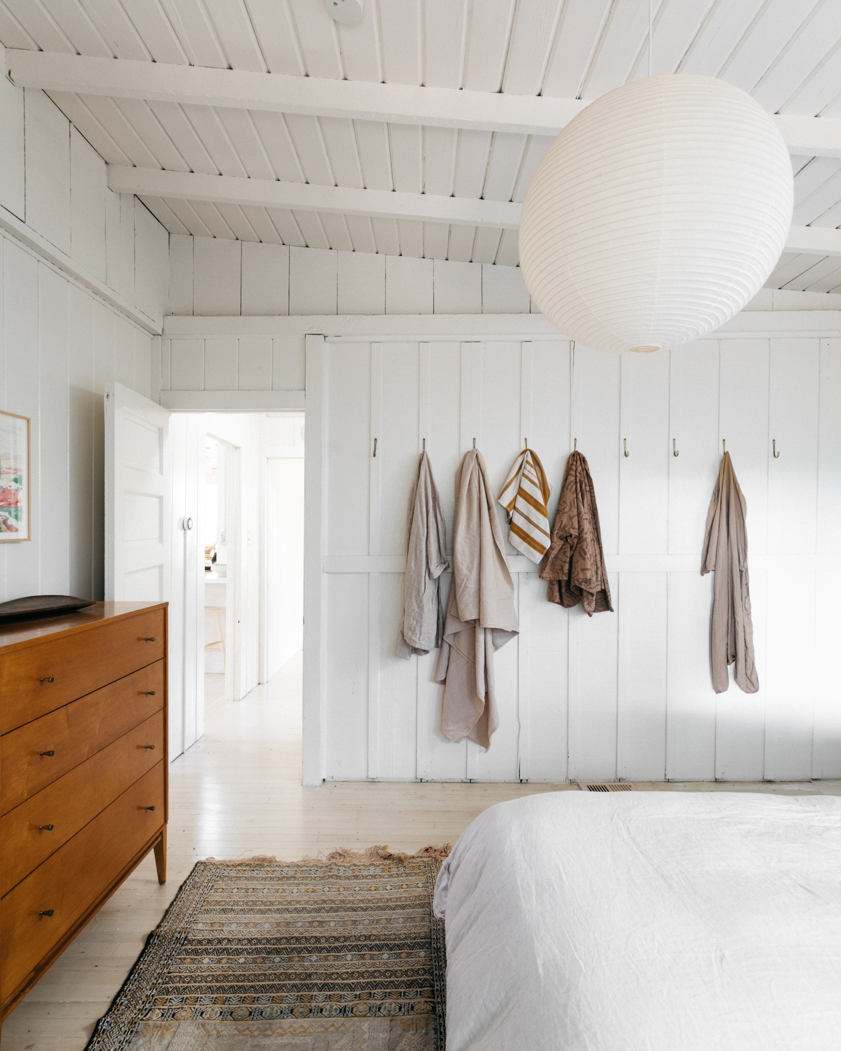 white bedroom with blankets hanging on hooks